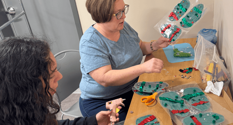 Two women sitting at a table with skateboards.