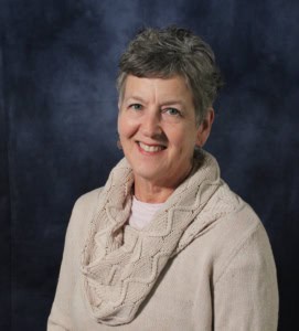 A woman in a tan jacket smiling for the camera.