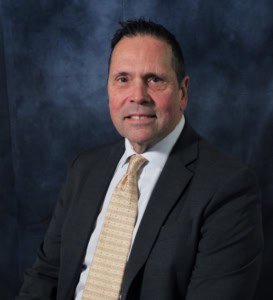 A man in suit and tie standing next to a wall.