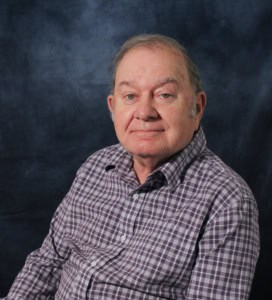 A man in a plaid shirt sitting down.